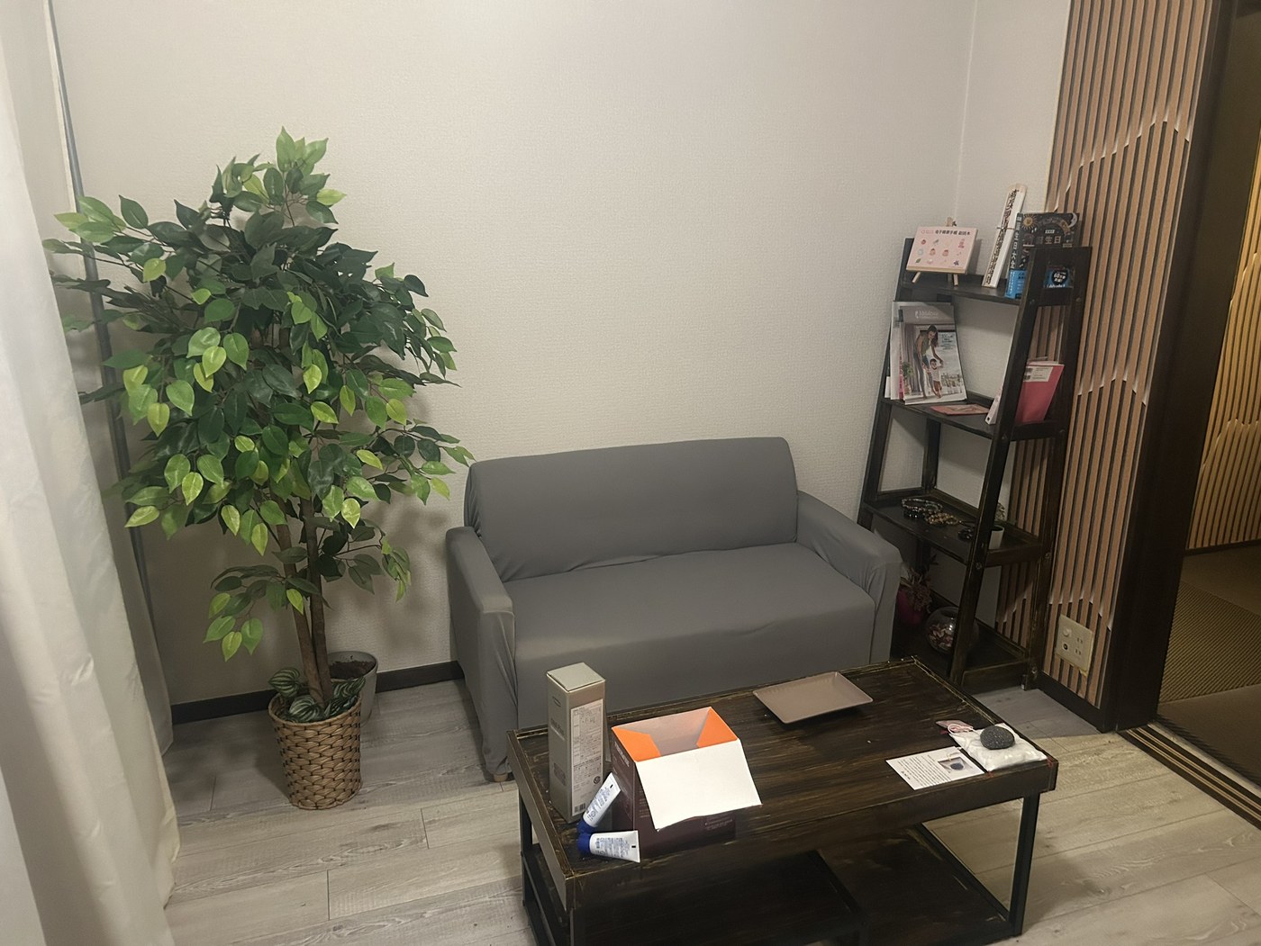 待合。ソファと観葉植物、書棚には育児関連の本が並びます